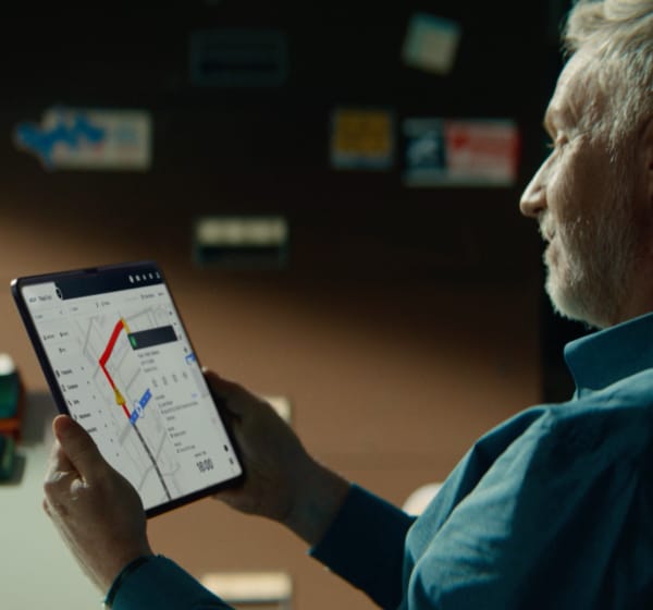Älterer Mann mit einem Tablet, auf dem Fahrzeugflottenanalysen angezeigt werden